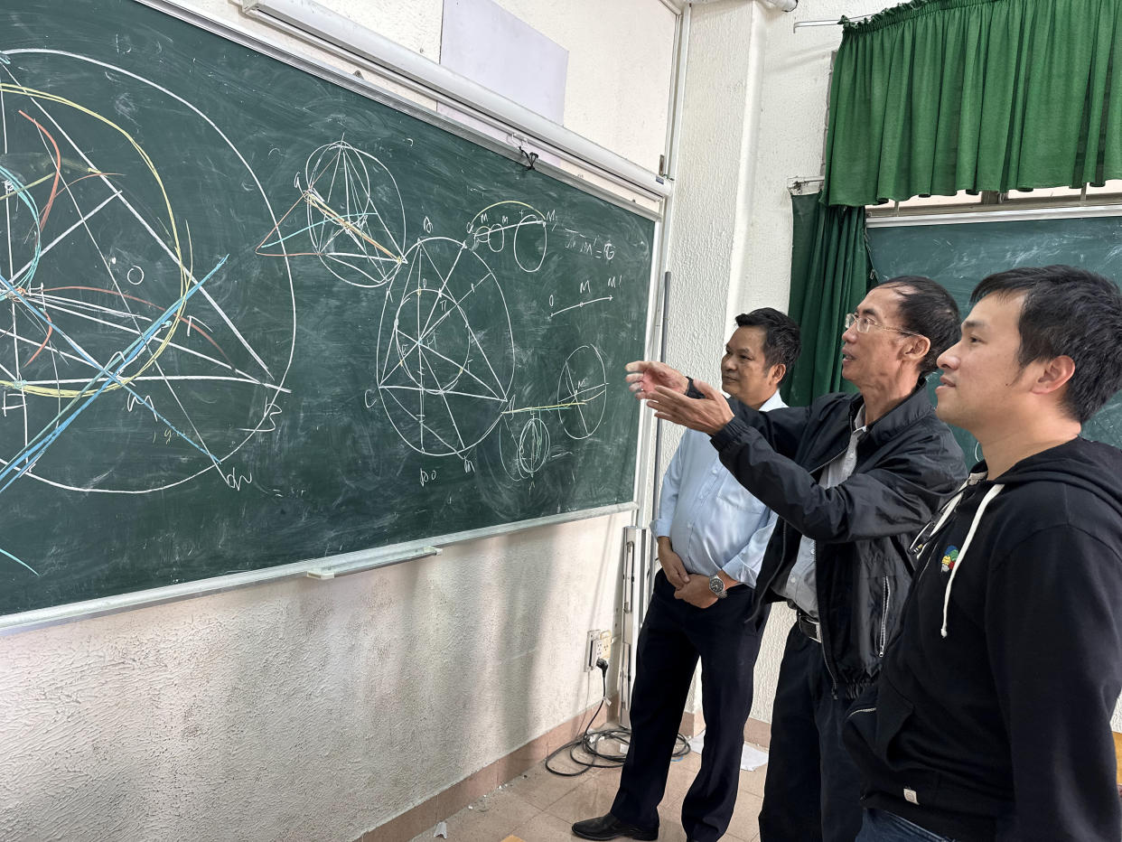 Thang Luong, a la derecha, analiza un problema de geometría de la Olimpiada Internacional de Matemáticas de 2015 con sus maestros, Trinh Le, al centro, y Dung Tran, en la ciudad de Ho Chi Minh, Vietnam, en diciembre de 2023. (Wendy Nguyen vía The New York Times)