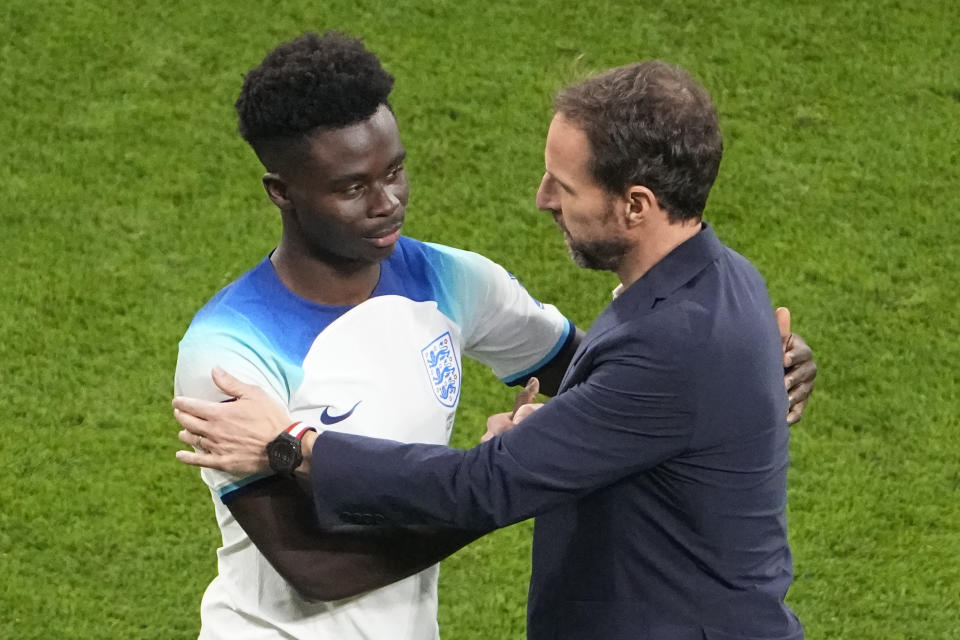 England's Bukayo Saka, left, and head coach Gareth Southgate shake hands after the World Cup group B soccer match between England and Iran at the Khalifa International Stadium in Doha, Qatar, Monday, Nov. 21, 2022. (AP Photo/Pavel Golovkin)