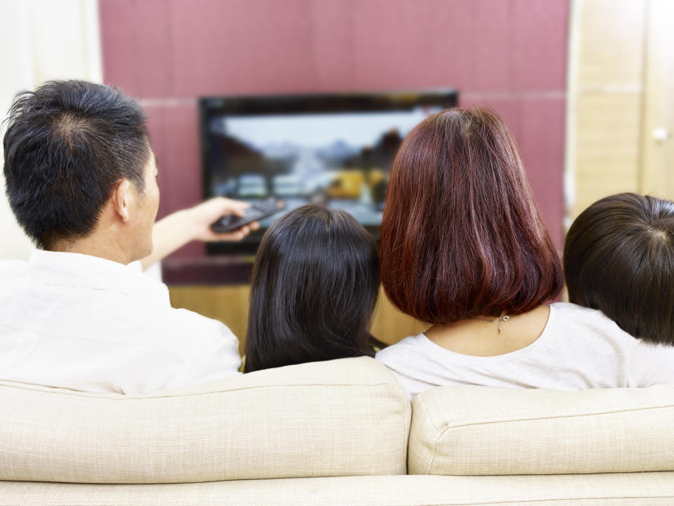 A family sitting on the couch watching television