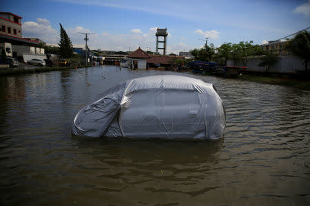 A car is seen stranded at a car park area as rising sea water hits Muara Baru fishing port during high tide in Jakarta, Indonesia, December 6, 2017. REUTERS/Beawiharta