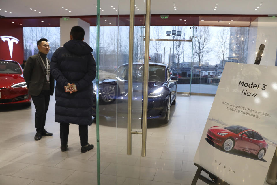 A sales staff chats with a customer at a Tesla store near a poster announcing orders of the Model 3 electric cars in Beijing, China, Monday, Jan. 7, 2019. Tesla Motors CEO Elon Musk said Monday on Twitter that the automaker is breaking ground for a Shanghai factory and will start production of its Model 3 by the end of the year. (AP Photo/Ng Han Guan)