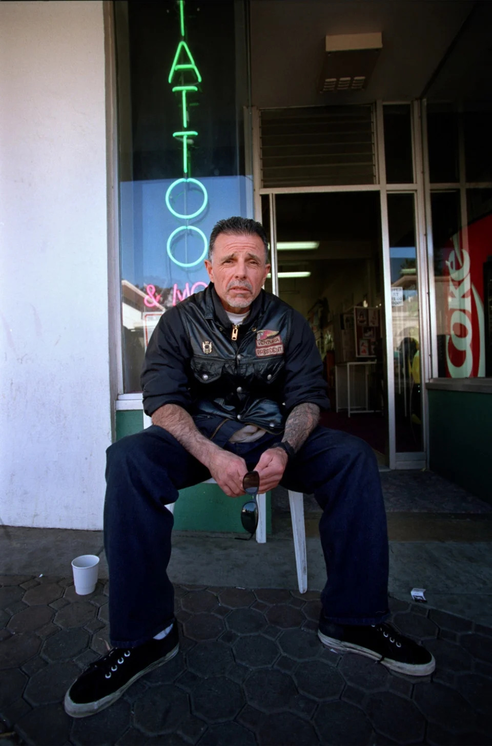 George Christie sitting in front of a tattoo shop.