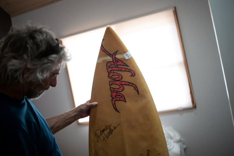 Australian surfer David Ford shows one of the few remaining surfboards of his vintage surfboard collection that was destroyed in the recent bushfires in Lake Conjola