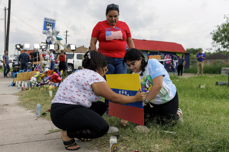 FILE - Patty Limon watches her daughters Annaalexis Limon and Monica Limon place a Venezuelan flag, painted by Annaalexis, at a memorial where eight migrants were killed, and several others injured the day before while waiting at a bus stop in Brownsville, Texas, Monday, May 8, 2023. A Texas jury has found George Alvarez guilty of intoxication manslaughter, Friday, June 28, 2024 over the deaths of eight people who were struck by an SUV that plowed into a crowded bus stop outside a migrant shelter on the U.S.-Mexico border. (AP Photo/Michael Gonzalez, File)