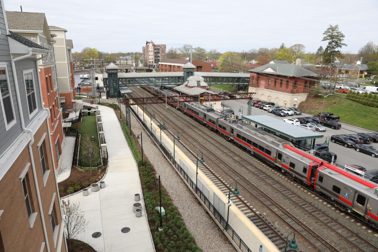 A train arrives at the Harrison Metro-North station beside the Avalon Harrison, left, as seen from atop a commuter parking garage April 19, 2024 in Harrison. The Avalon Harrison, which has 143 apartment units in three residential buildings next to the train station, was a Metro-North led transit oriented development project completed in 2023.