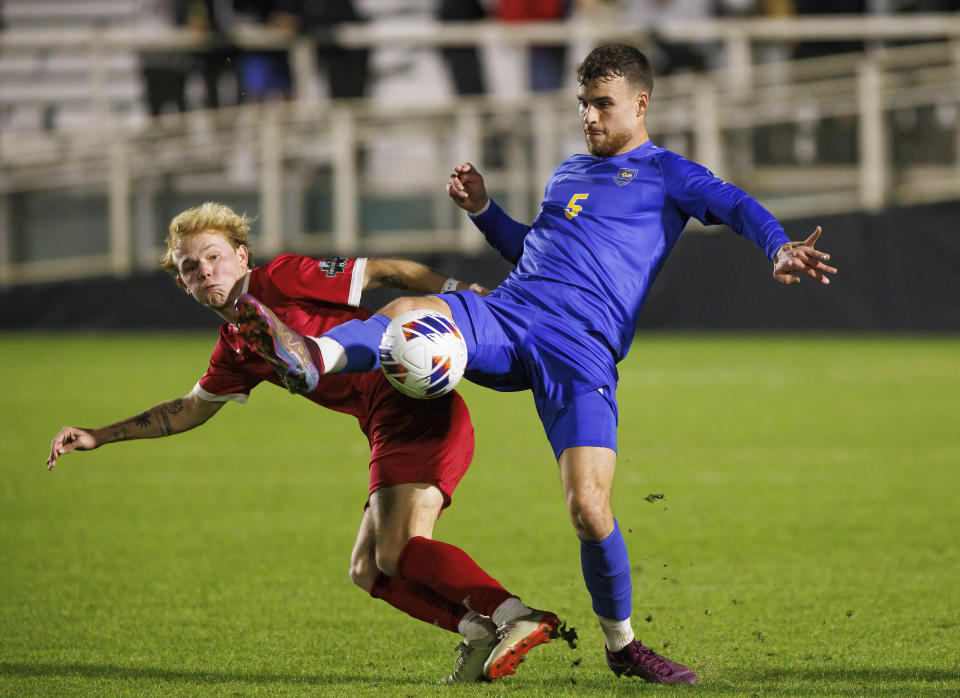 Pittsburgh's Yanis Leerman (5) kicks the ball next to Indiana's Samuel Sarver during the first half of an NCAA men's soccer tournament semifinal in Cary, N.C., Friday, Dec. 9, 2022. (AP Photo/Ben McKeown)