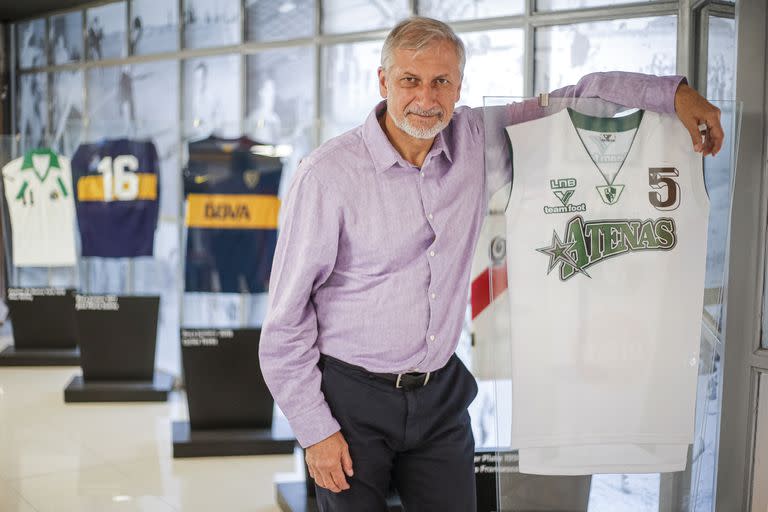 Héctor "Pichi" Campana posa junto a una camiseta de Atenas usada por él en sus tiempos de basquetbolista; detrás, testimonios célebres del fútbol.