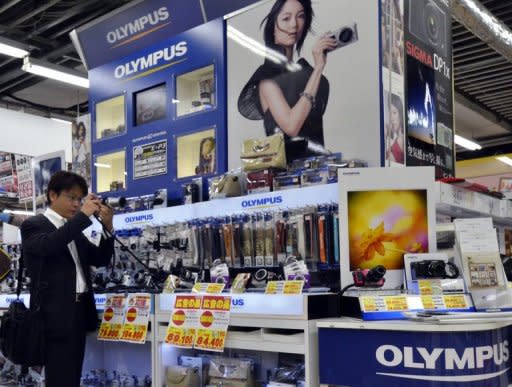 A customer checks a camera of Japanese optical giant Oltmpus at a Tokyo camera shop. The ousted former boss of Olympus who exposed a $1.7 billion cover-up scandal threatened court action after the firm's choices for a new board were approved at a heated shareholders meeting
