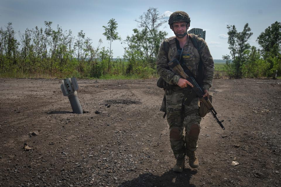 A soldier walking while carrying a gun.