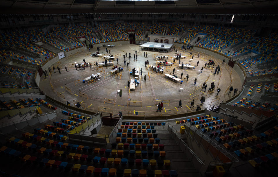 People line up and cast their votes at a polling station set up at the Tarraco Arena Plaza, a former renamed Tarragona Bullring, during regional Catalan election in Tarragona, Spain, Sunday, Feb. 14, 2021. Over five million voters are called to the polls on Sunday in Spain's northeast Catalonia for an election that will measure the impact of the coronavirus pandemic on the restive region's secessionist movement. (AP Photo/Emilio Morenatti)