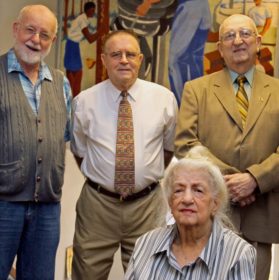 Retired art teacher Virginia Goson takes a portrait with former students Guy Thrams, David Robinson and Jim Dorton in 2011 in front of the mural they created in 1947 at Lawndale Elementary School in Akron.