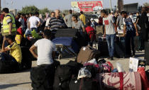 Passengers sit next to their luggage as they wait to cross the border to the Egyptian side of Rafah crossing, in Rafah, Gaza Strip, Tuesday, Aug. 11, 2020. Egypt reopened Rafah Crossing for three days starting Tuesday for humanitarian cases in and out of the Gaza Strip, including medical patients and people who had Egyptian and international citizenship. The border was closed since March. (AP Photo/Adel Hana)