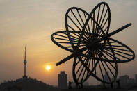 The sun sets over the television tower along the Yangtze River in Wuhan in central China's Hubei province on Wednesday, April 8, 2020. Streets in the city of 11 million people were clogged with traffic and long lines formed at the airport, train and bus stations as thousands streamed out of the city to return to homes and jobs elsewhere. Yellow barriers that had blocked off some streets were gone, although the gates to residential compounds remained guarded. (AP Photo/Ng Han Guan)