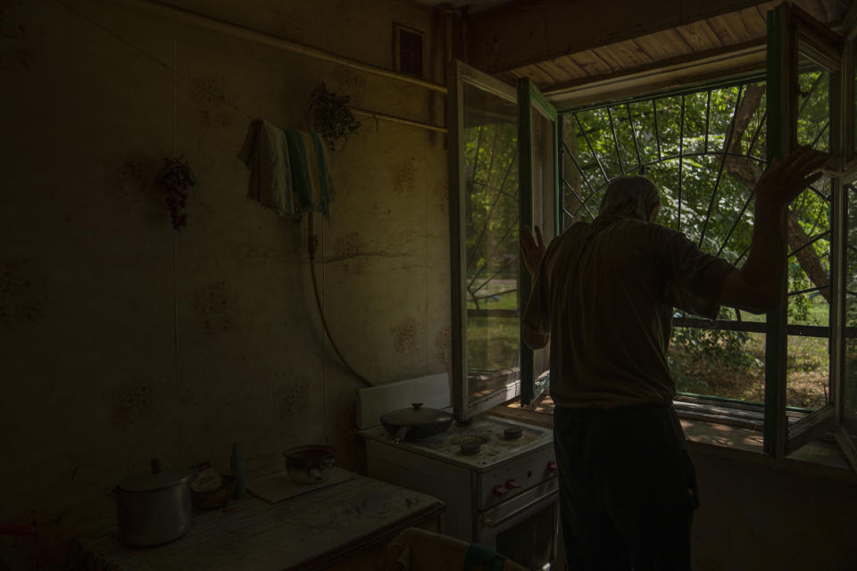 Seventy-year-old pensioner Valerii Ilchenko, who lives alone and is refusing to evacuate, opens the windows of the kitchen in his apartment, in Kramatorsk, eastern Ukraine, Wednesday, July 6, 2022. Now a widower, Ilchenko says he still has no intention of leaving. "I don't have anywhere to go and don't want to either. What would I do there? Here at least I can sit on the bench, I can watch TV," he says in an interview in his single-room apartment. (AP Photo/Nariman El-Mofty)