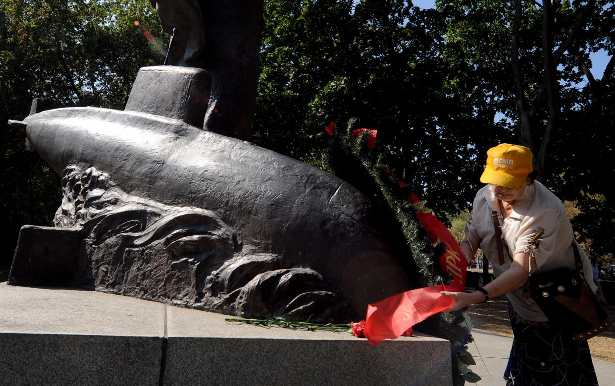 A Russian woman adjusts a wreath at a monument in Moscow to those who died in the Kursk submarine disaster