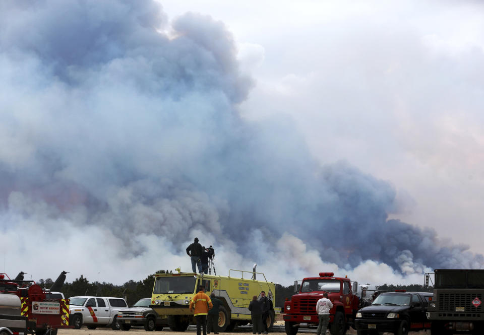 Spectators watch as the Spring Hill fire and backfire burns in Woodland Township, N.J., Sunday, March, 31, 2019. Authorities say fire whipped by high winds has spread over thousands of acres of state forest land in the Pinelands of New Jersey. (Ed Murray/NJ Advance Media via AP)