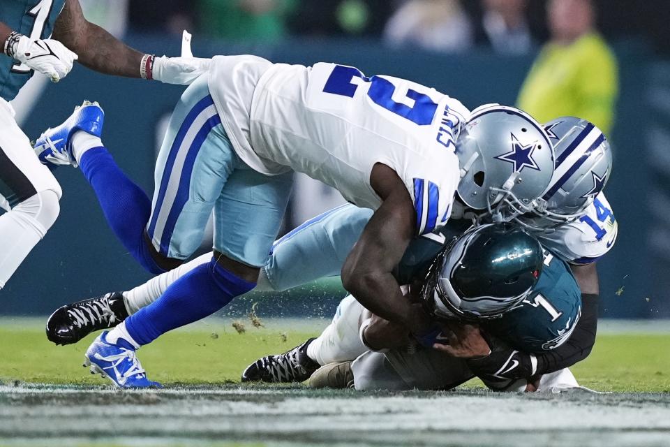 Philadelphia Eagles quarterback Jalen Hurts (1) is stopped by Dallas Cowboys safety Markquese Bell (14) and Cowboys' cornerback Jourdan Lewis (2) during the first half of an NFL football game Sunday, Nov. 5, 2023, in Philadelphia. (AP Photo/Matt Rourke)