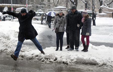 A man jumps over a puddle in the rain in the Manhattan borough of New York February 5, 2014. REUTERS/Carlo Allegri