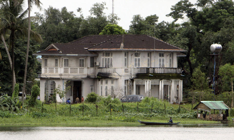 FILE - A man rows a boat past the lake side home of Myanmar's pro-democracy leader Aung San Suu Kyi on Aug. 11, 2009, in Yangon, Myanmar. A court in military-controlled Myanmar has ordered that the family home of the country’s ousted leader Aung San Suu Kyi, where she spent 15 years under house arrest, be put on auction in March, issuing its ruling after a decades-long legal dispute between her and her brother. (AP Photo/Khin Maung Win, File)