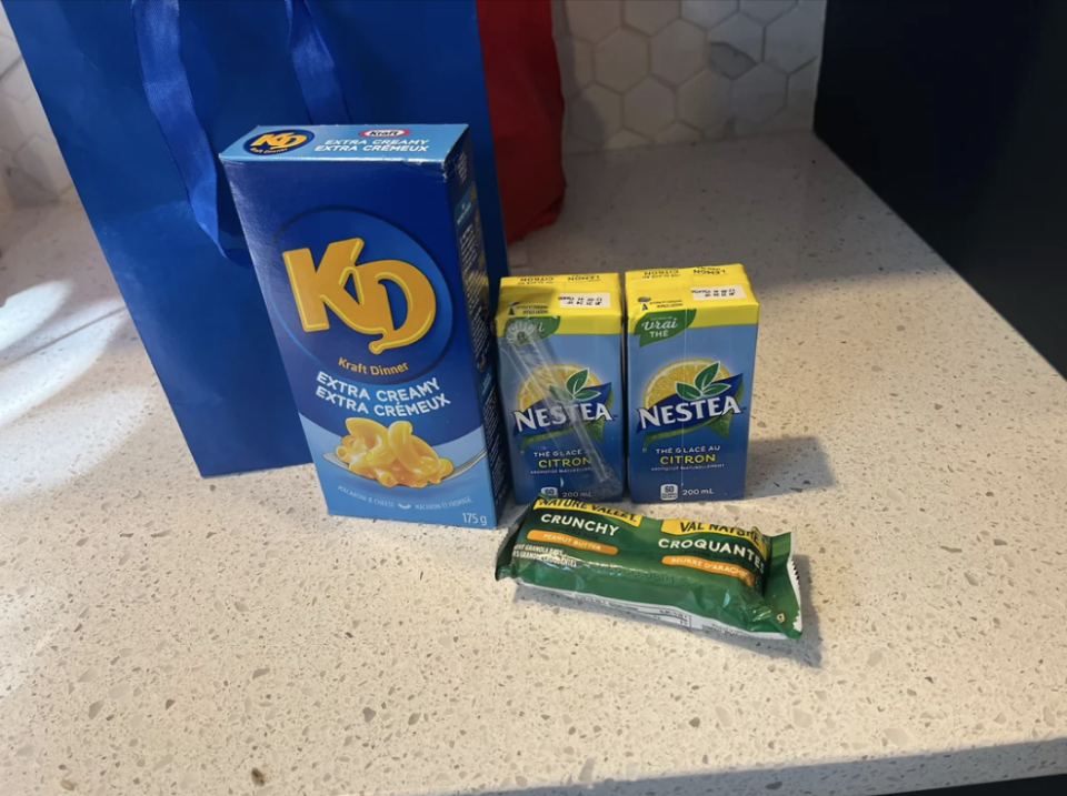 A box of kraft mac n'cheese, a nature valley bar, and 2 juice boxes on a countertop