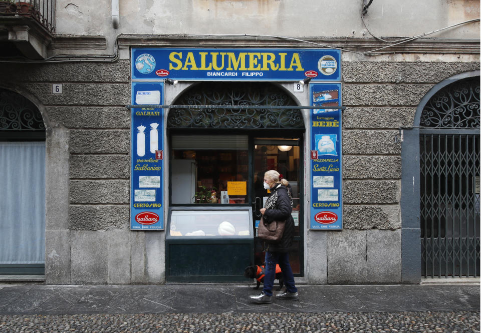 In this photo taken on Thursday, March 12, 2020, a woman walks past a deli meat and cold cuts shop in Codogno, Italy. The northern Italian town that recorded Italy’s first coronavirus infection has offered a virtuous example to fellow Italians, now facing an unprecedented nationwide lockdown, that by staying home, trends can reverse. Infections of the new virus have not stopped in Codogno, which still has registered the most of any of the 10 Lombardy towns Italy’s original red zone, but they have slowed. For most people, the new coronavirus causes only mild or moderate symptoms. For some it can cause more severe illness. (AP Photo/Antonio Calanni)