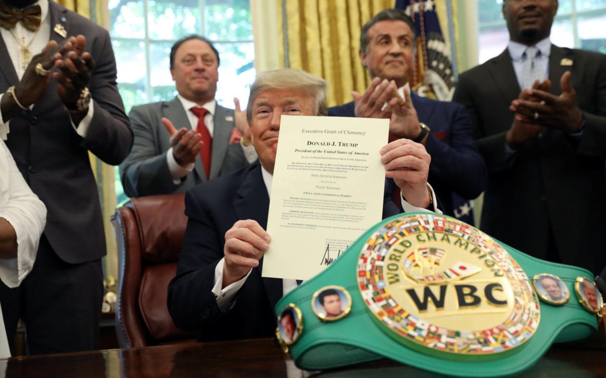 Sylvester Stallone and Lennox Lewis watch on as the president signs the pardon  - REUTERS