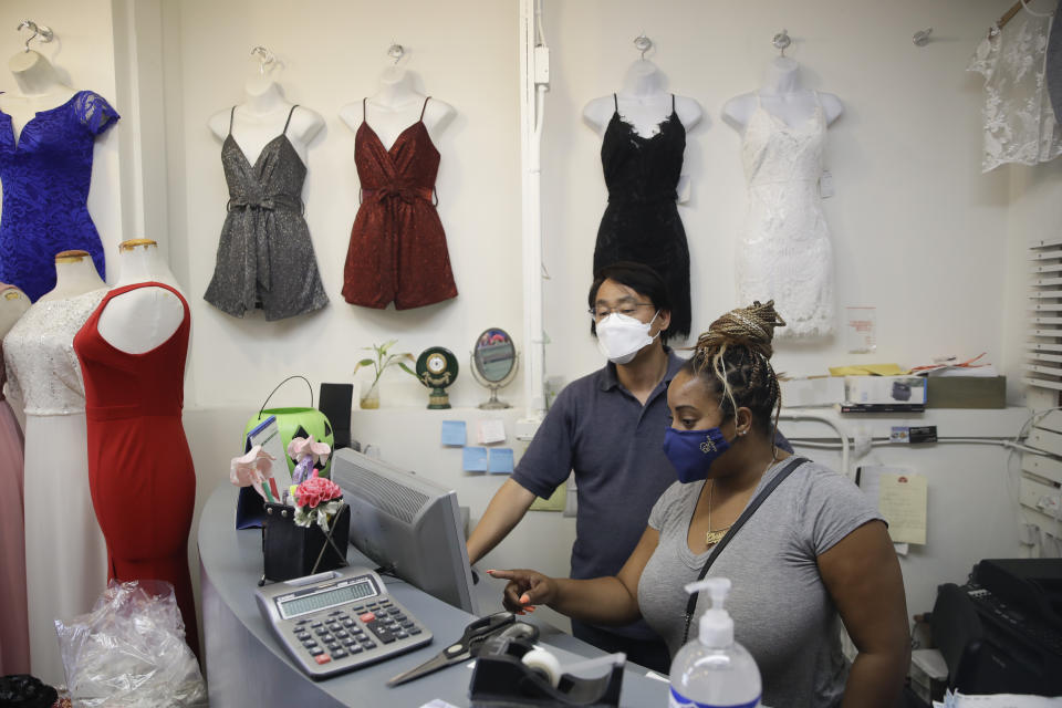 Christina Anderson, right, shops for fashion in bulk for the store RichNPure with the help of a store owner Wednesday, May 27, 2020, in Los Angeles. California moved to further relax its coronavirus restrictions and help the battered economy. Retail stores, including those at shopping malls, can open at 50% capacity. (AP Photo/Marcio Jose Sanchez)