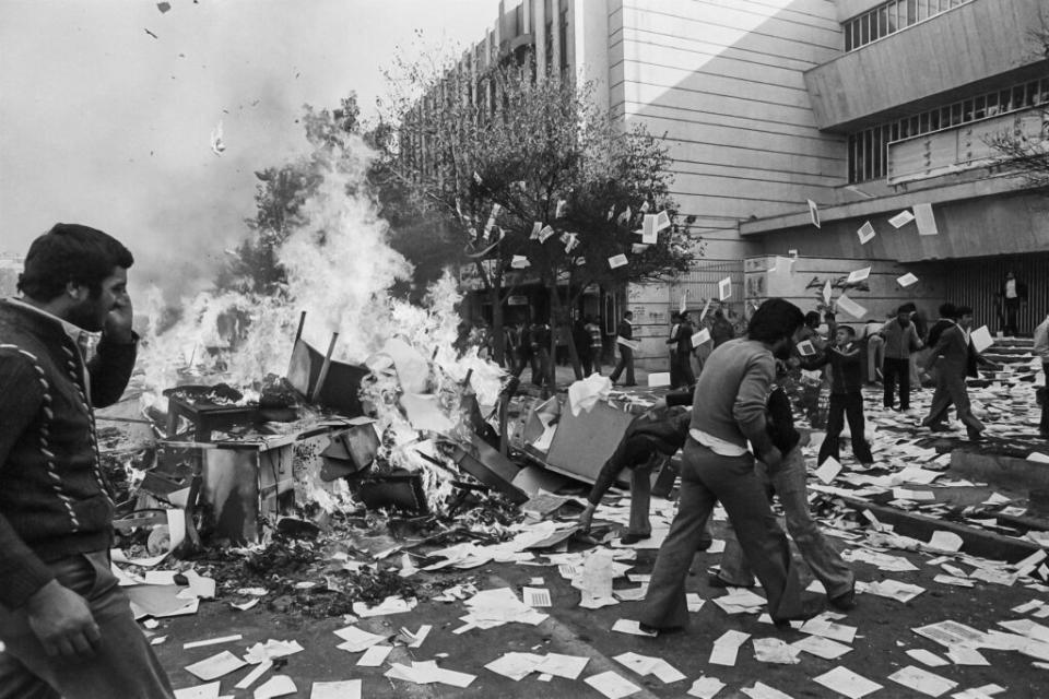 Demonstrators loot government bureaus and banks as well as liquor shops, cabarets and cinemas during the Revolution in Tehran, 4th November 1978. Documents thrown out of the buildings are spread on the street while furniture is set ablaze. (Credit: Kaveh Kazemi/Getty Images)