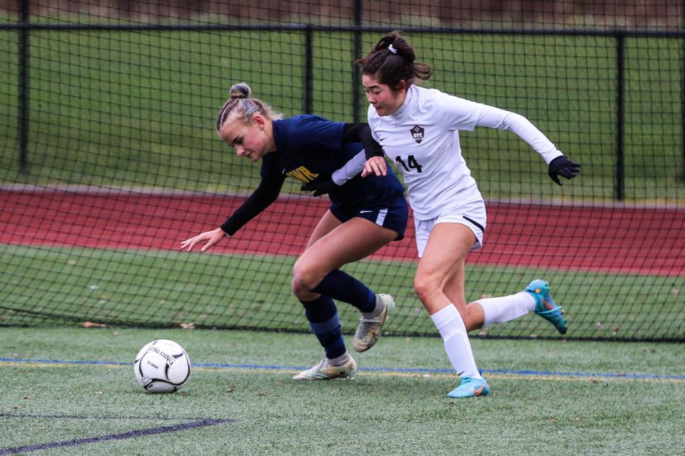 Shoreham-Wading River's Johanna Ochsenfeld (blue) battles with Rye's Mali White (14, white) for possession during the NYSPHSAA Class A girls soccer state championship match at Cortland High School on Sunday, Nov. 12, 2023.