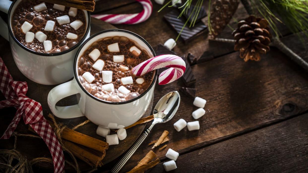 two homemade hot chocolate mugs with marshmallows on rustic wooden christmas table