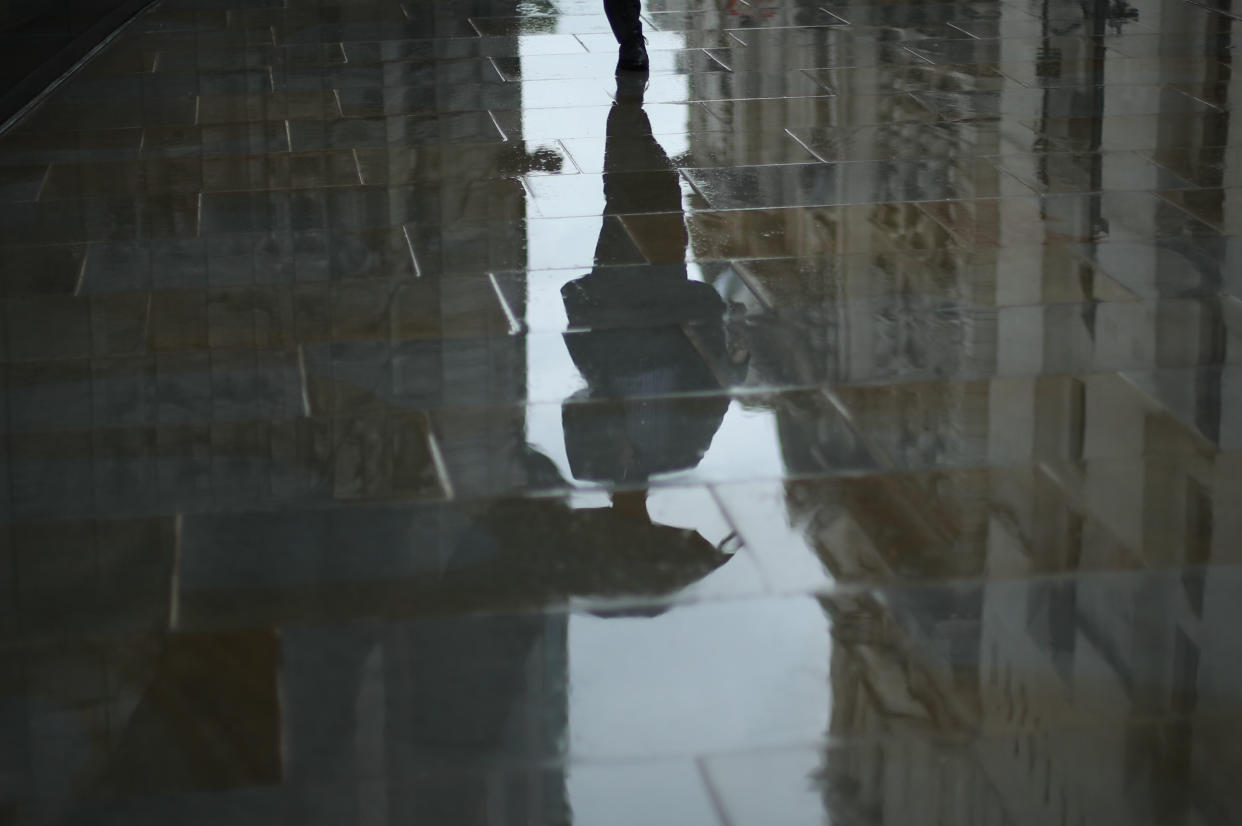 A man with an umbrella is reflected in the wet pavement outside the Old Bailey, London following a rain shower (Picture: PA)