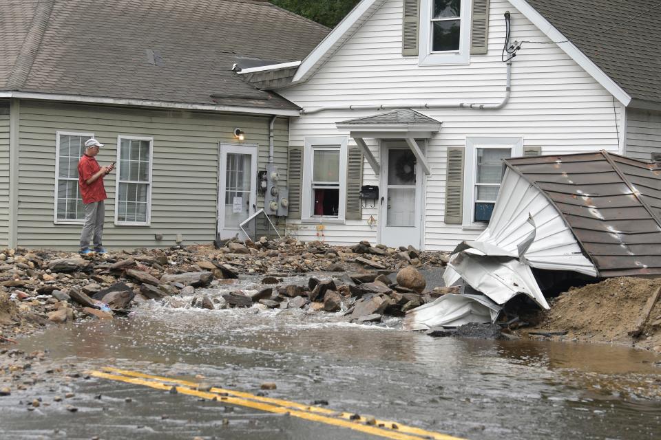 A man surveys damage to a house on Hamilton Street in Leominster, Mass. after heavy rain fall in the town overnight (Copyright 2023 The Associated Press. All rights reserved)