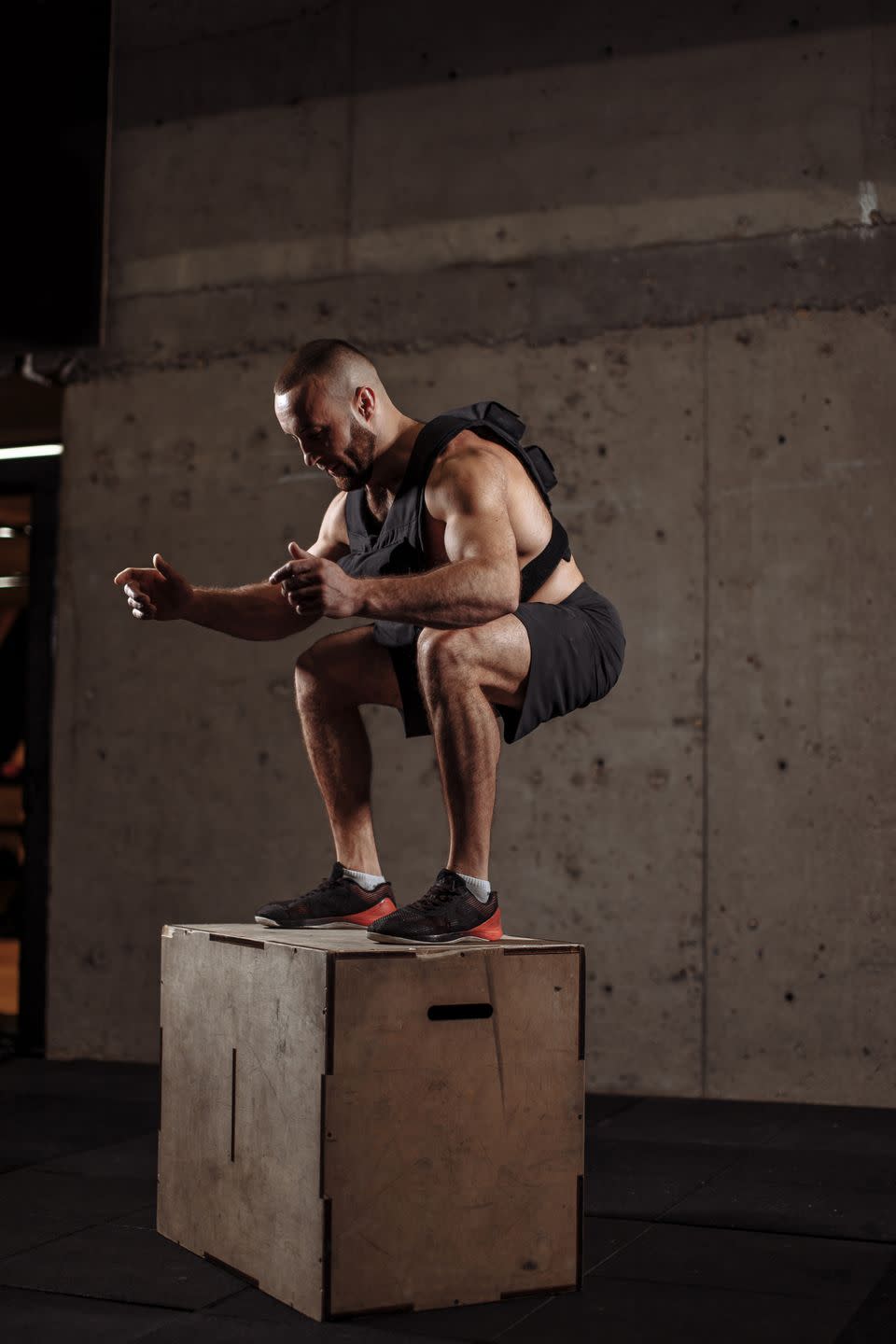 strong sportsman is doing squats on a s box at the gym