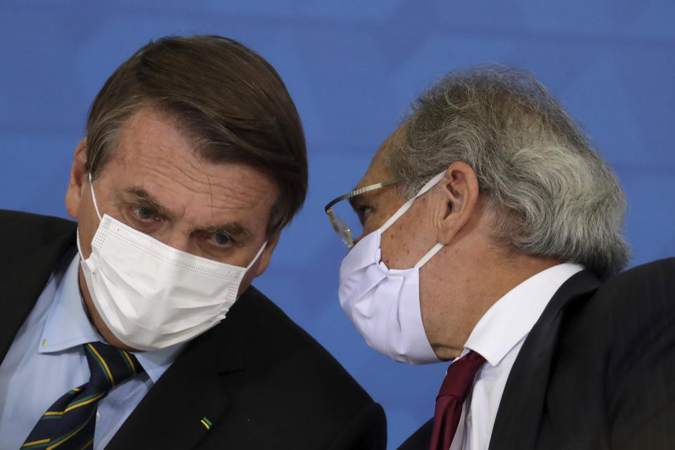 Brazil's President Jair Bolsonaro and Economy Minister Paulo Guedes wear protective face masks during a ceremony announcing economic measures to support philanthropic hospitals and help them treat COVID-19 patients, at the Planalto Presidential Palace, in Brasilia, Brazil, Thursday, March 25, 2021. (AP Photo/Eraldo Peres)