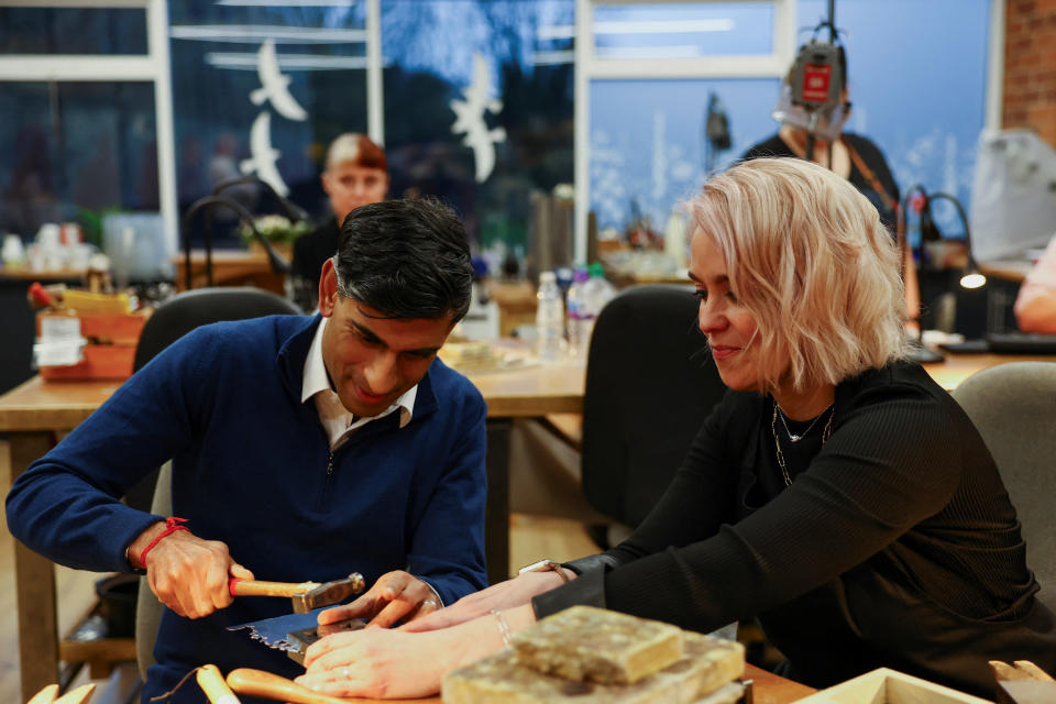 FARSLEY, UNITED KINGDOM - NOVEMBER 23:  British Prime Minister Rishi Sunak, next to Emma White, hammers a piece of jewellery during a meeting with small business owners from Sunny Bank Mills, at The Emma White Jewellery Studio in Sunny Bank Mills on November 23, 2023, Farsley, England.  (Photo by Molly Darlington/WPA Pool/Getty Images)