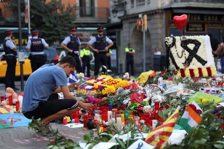 A man lights a candle at an impromptu memorial where a van crashed into pedestrians at Las Ramblas in Barcelona, Spain August 21, 2017. REUTERS/Susana Vera