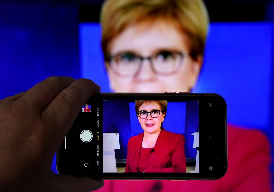 A person uses their phone to film a televised broadcast of First Minister Nicola Sturgeon (Andrew Milligan/PA) (PA Wire)