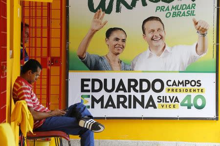 Members of a campaign committee are pictured next to a campaign sign of the late presidential candidate Eduardo Campos and his vice-presidential candidate Marina Silva, in Recife August 14, 2014. REUTERS/Ricardo Moraes