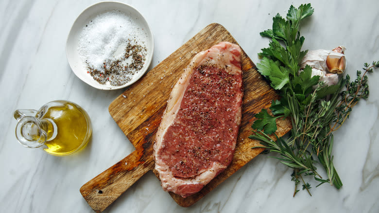 raw steak on board with seasonings