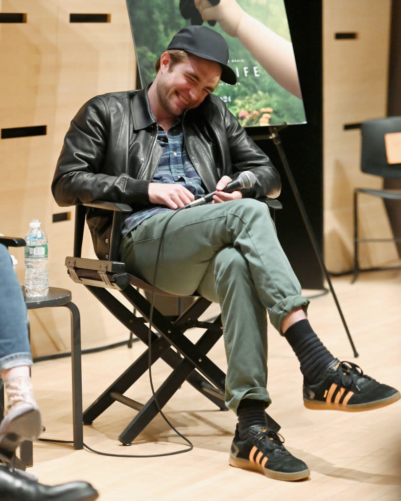 sitting on stage to give a talk, Rob tucks his face into his shoulder to hide his huge smile