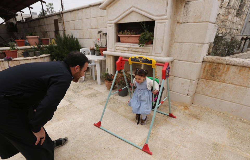 In this Sunday, Feb. 23, 2020 photo, Abdullah Mohammed plays with his daughter, three-year-old Salwa at a house he recently fled to, near the Syrian-Turkish border, in Sarmada, Syria. Mohammed would do anything for his daughter, even if that means forcing himself to laugh with her at the sound of exploding bombs, to help her overcome her fear. Mohammed and Salwa became an overnight celebrity after a video they shot spread on social media, widely shared as a reminder of the horrors faced by children in Syria. (AP Photo/Ghaith Alsayed)