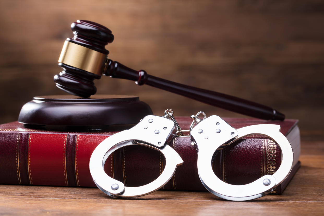 Gavel And Handcuffs On The Law Book Over The Wooden Table Background