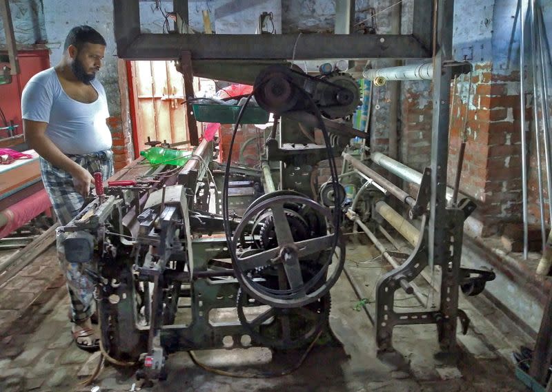 Mohammad Kasim, one of the power loom owners, poses next to his loom in Varanasi