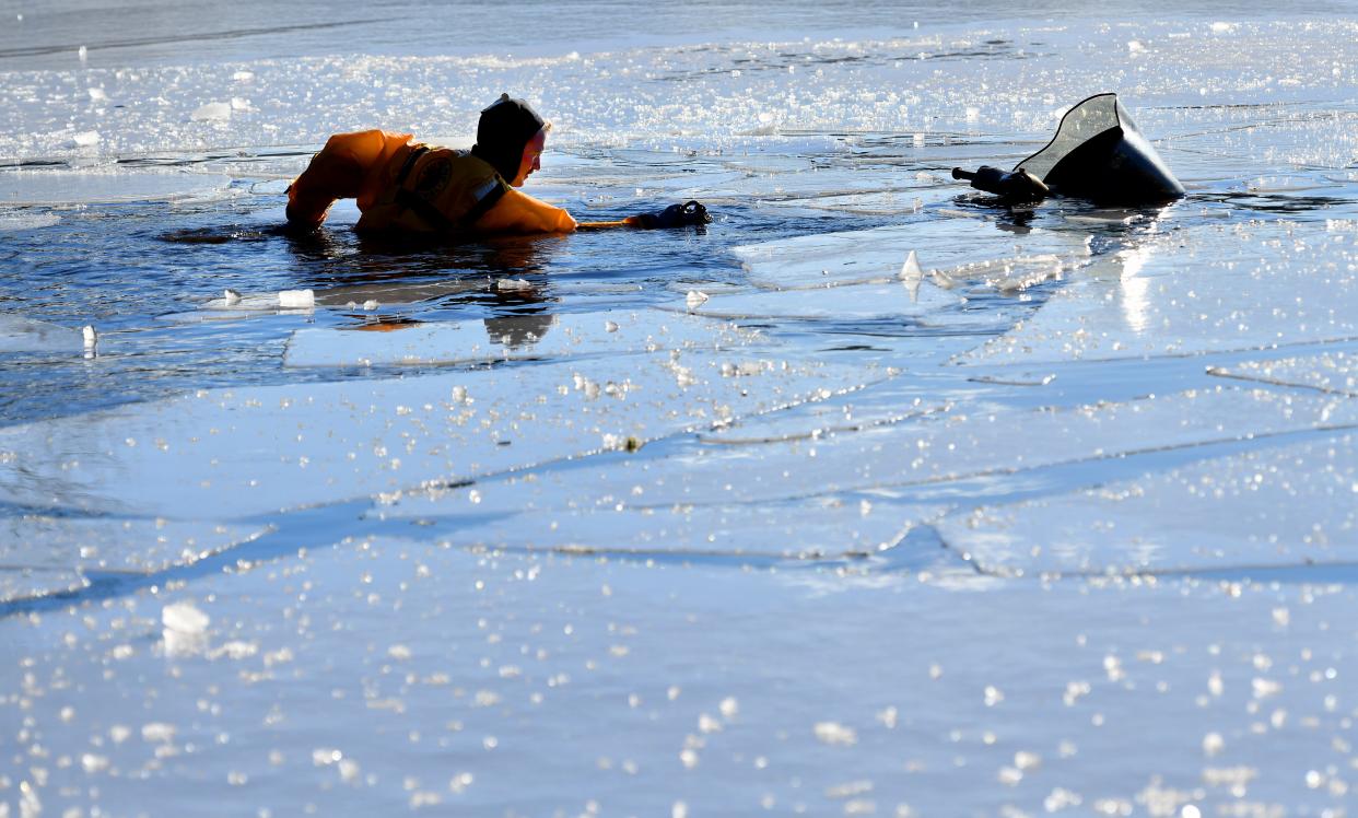 Shrewsbury firefighter Owen Bouffard carries a tow-truck chain as he makes his way to a mostly submerged snowmobile that had broken through the ice along with its driver at Jordan Pond Tuesday afternoon.