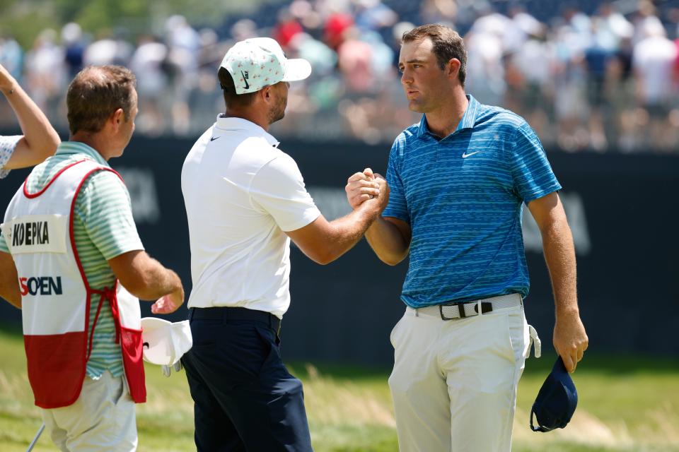 Brooks Koepka of the United States and Scottie Scheffler of the United States shake hands on the 18th green as caddie Ricky Elliott looks on during the second round of the 122nd U.S. Open Championship at The Country Club on June 17, 2022 in Brookline, Massachusetts. (Photo by Jared C. Tilton/Getty Images)