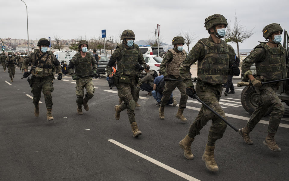 Spanish Army soldiers run as they take positions at the border of Morocco and Spain, at the Spanish enclave of Ceuta, on Tuesday, May 18, 2021. (AP Photo/Javier Fergo)