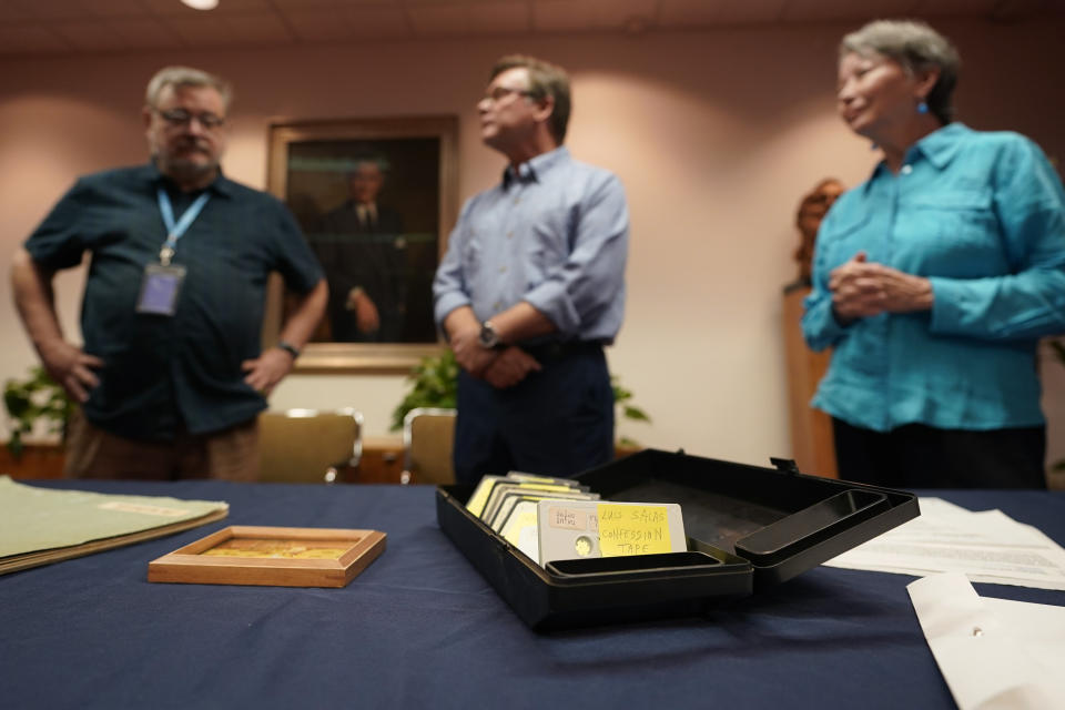 CORRECTS ID TO ARCHIVIST BRIAN MCNERNEY INSTEAD OF LIBRARY DIRECTOR MARK LAWRENCE - Peter Mangan, center, and his wife, Karen, right, stand with Lyndon B. Johnson presidential library archivist Brian McNerney, left, as they prepare to make a donation to the library, Wednesday, Aug. 31, 2022, in Austin, Texas. The family of late Associated Press reporter James W. Mangan has donated to the library cassette tapes containing interviews the reporter did that led to a 1977 story in which a Texas voting official detailed how three decades earlier, votes were falsified to give Johnson a slim victory in a U.S. Senate primary. (AP Photo/Eric Gay)