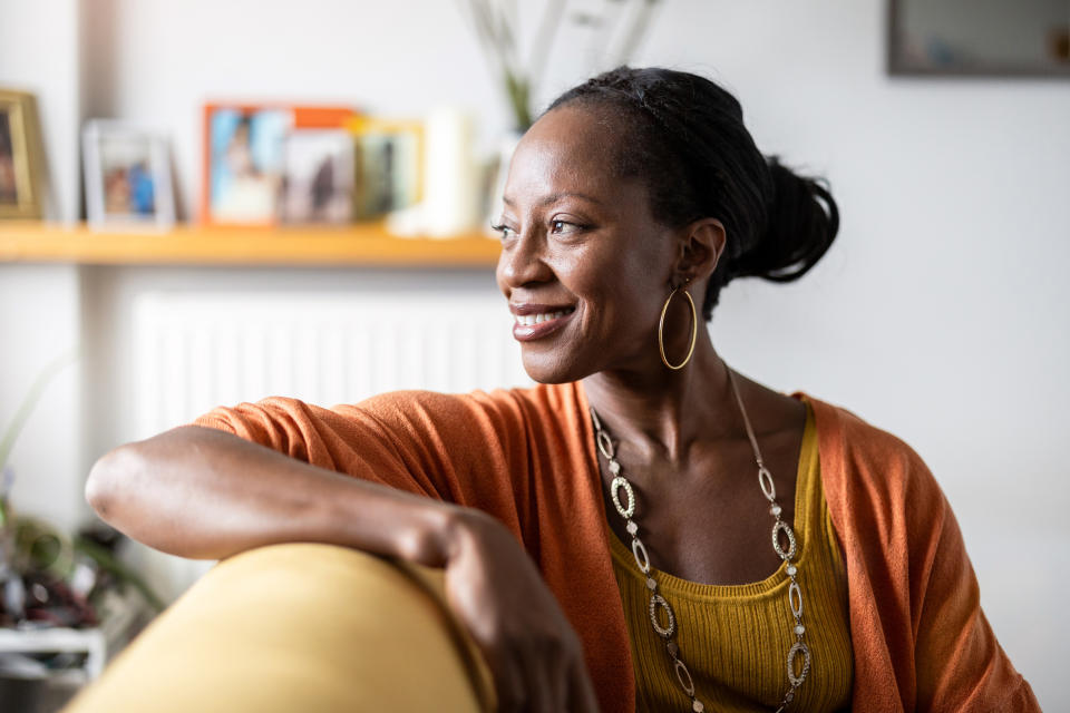 Woman smiling, looking away, sitting in a living room