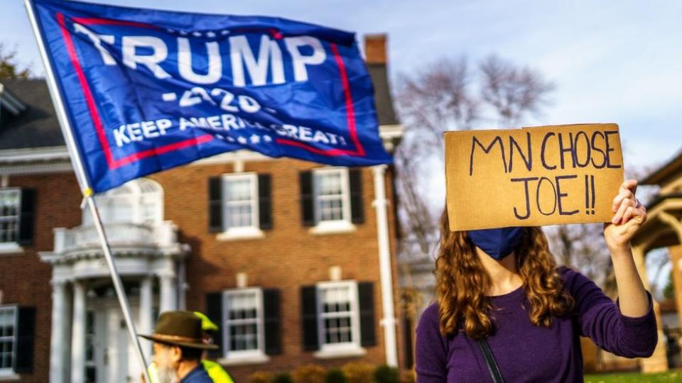 Votantes de Trump y Biden con carteles.