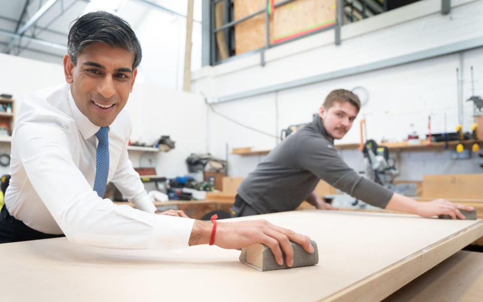 Prime Minister Rishi Sunak (left) helps to make a wooden door with carpentry apprentice Adam Jellis during a visit to Pinewood Studios in Buckinghamshire
